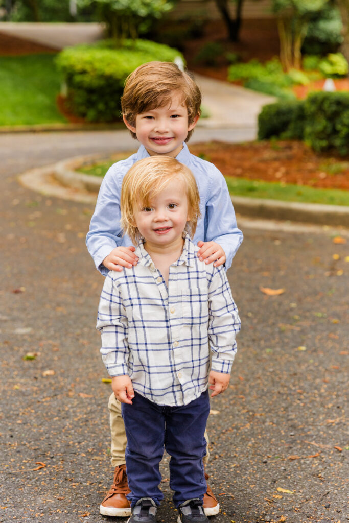 Sweet sibling portrait with older brother’s hands on little brother’s shoulders.