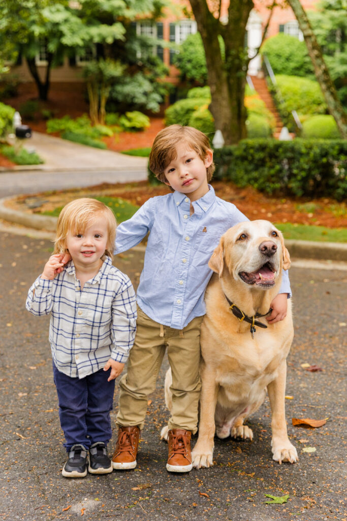 Two brothers and their dog standing together in their quiet Atlanta cul-de-sac.