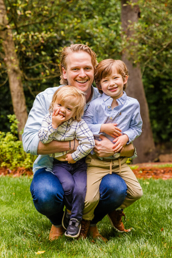 Father embraces his two sons in a playful, candid moment.