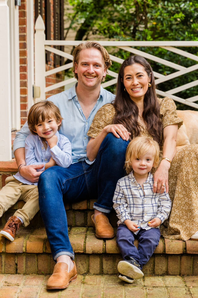 Family of four sitting on porch steps in matching outfits, smiling.