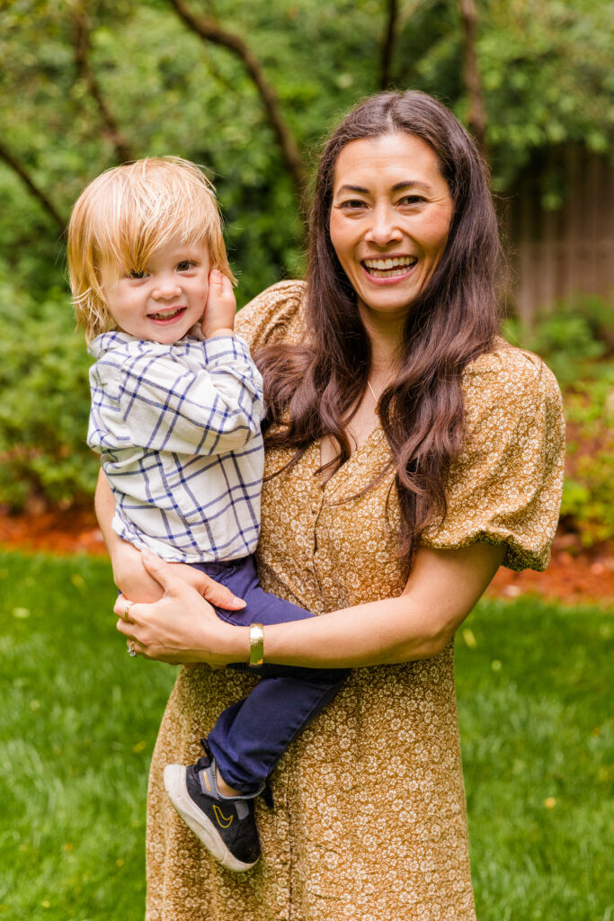 Mother holding toddler boy and laughing together at the camera.