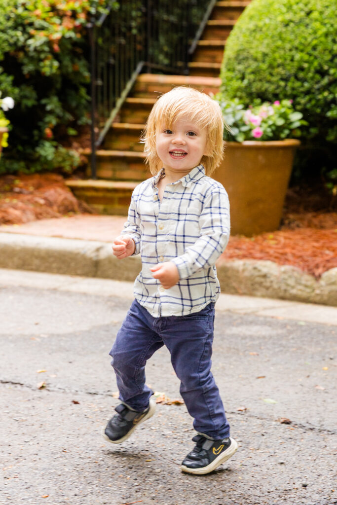 Young boy running in front of the house with joy.