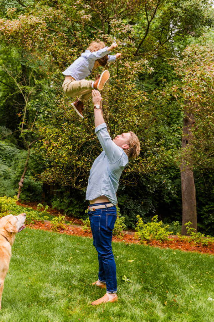 Father standing in the grass and lifting son joyfully in the air.