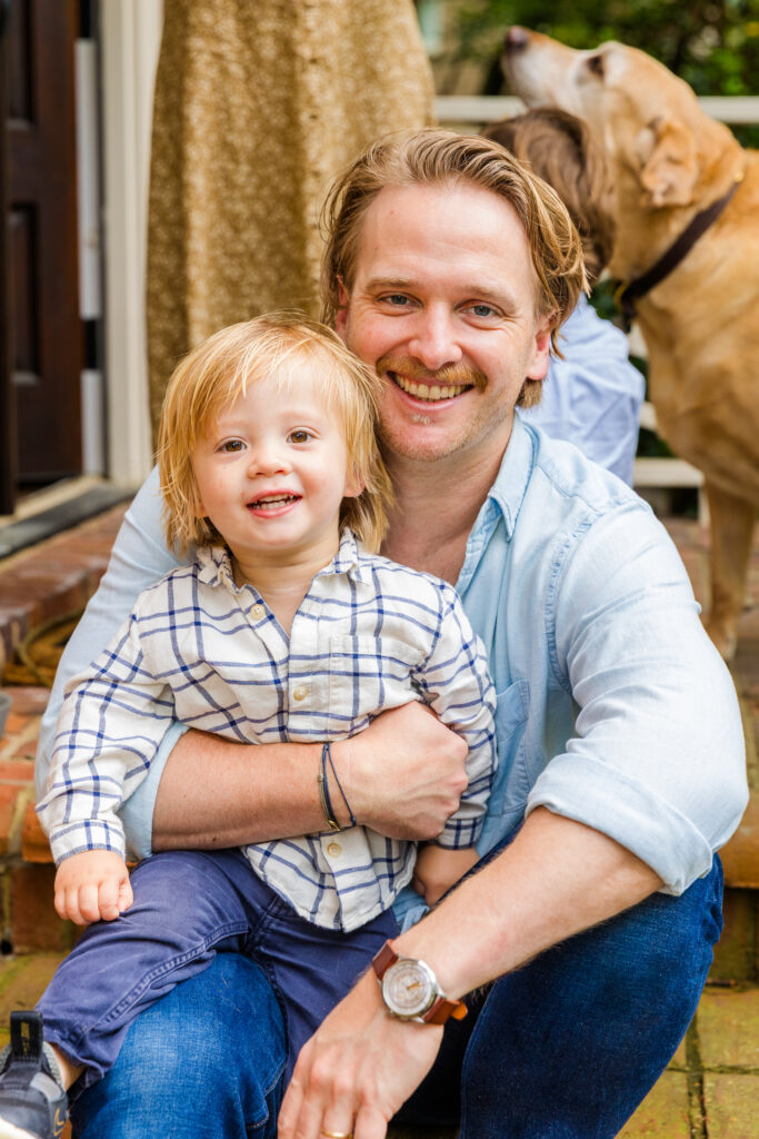 Dad sitting on steps holding son in matching blue and white outfits.