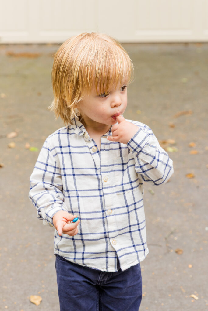 Toddler walking thoughtfully with one finger in his mouth.