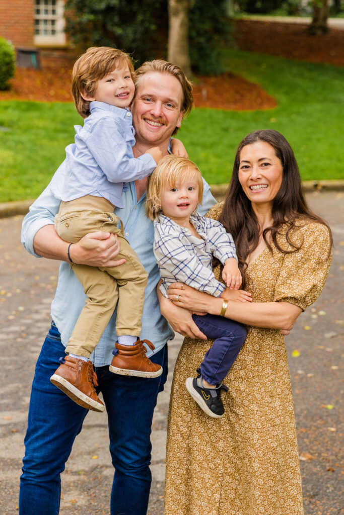 Family of four dressed in blue and beige outfits smiling during their Atlanta session.