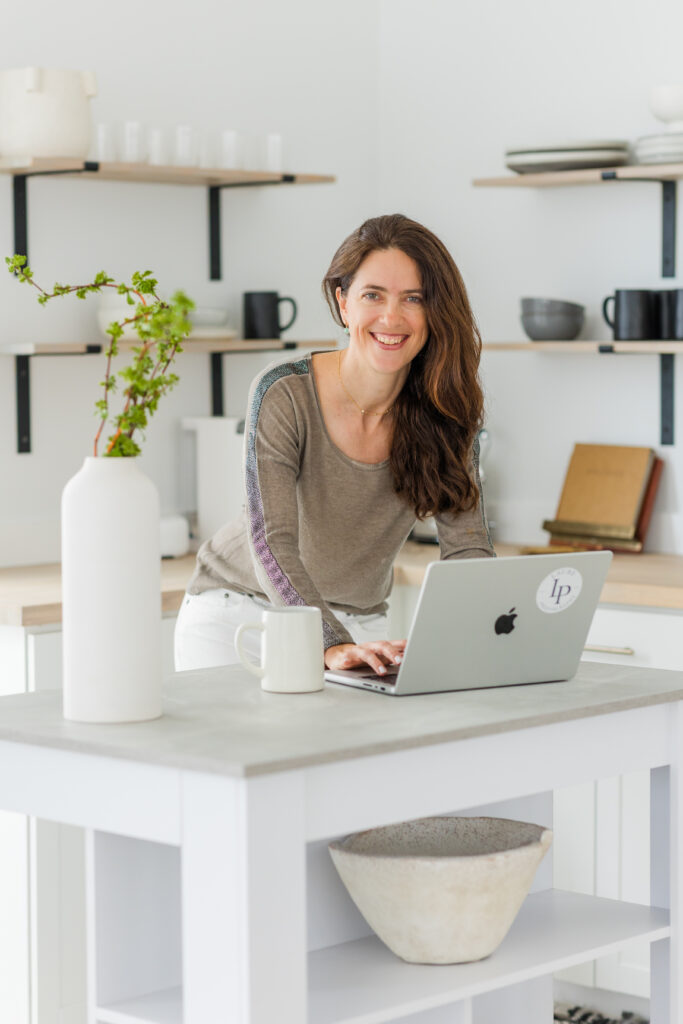 woman working on her laptop in her kitchen with a coffee mug with coordinating colors
