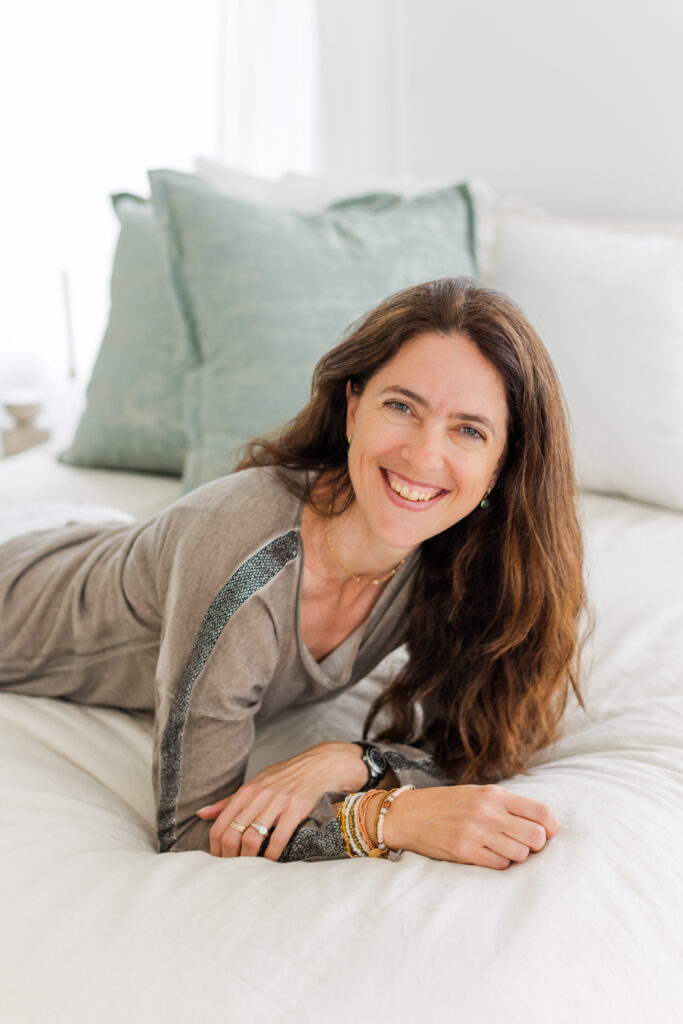 woman on a bed wearing a brown top long hair down up on her elbows