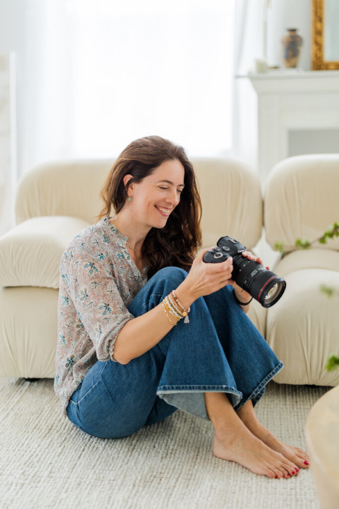 woman sitting on the floor in front of a sofa smiling at the back of the camera
