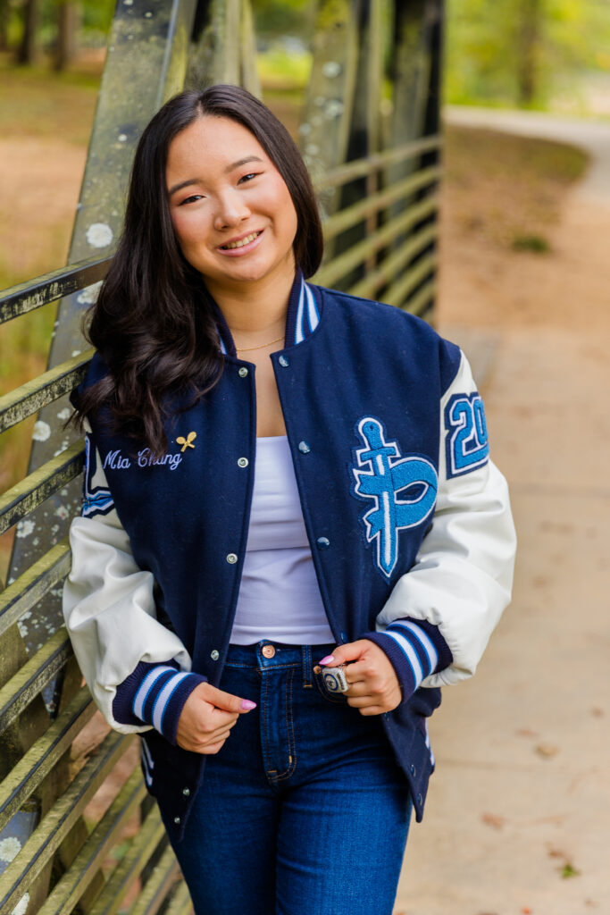 Mia leaning casually against the side of a wooden bridge in Brookhaven park.
