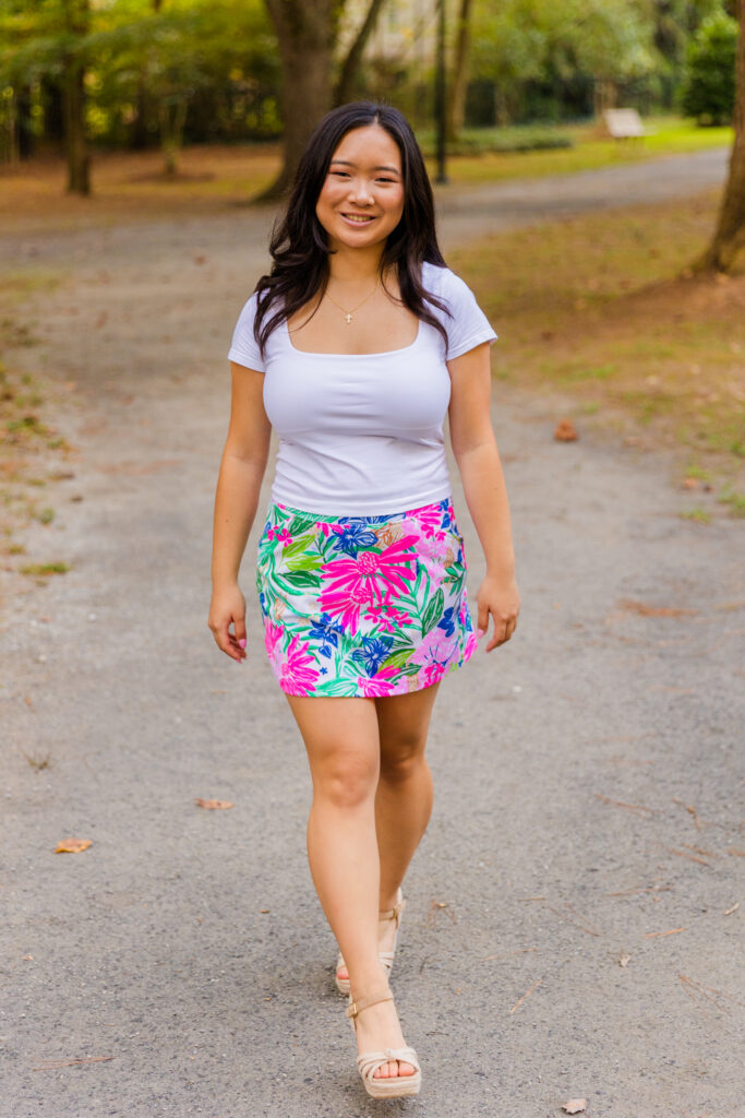 Pace Academy senior walking toward the camera wearing a colorful skirt and white top in Brookhaven.