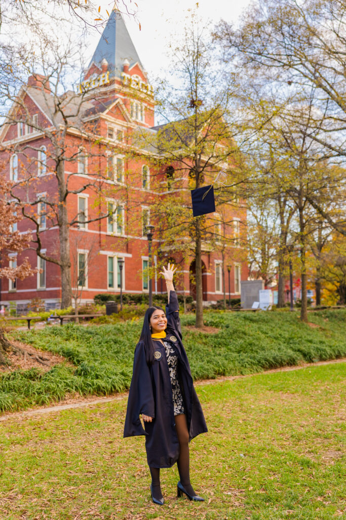 Pallovi throwing her graduation cap in the air on the grass with the Georgia Tech Tower behind her