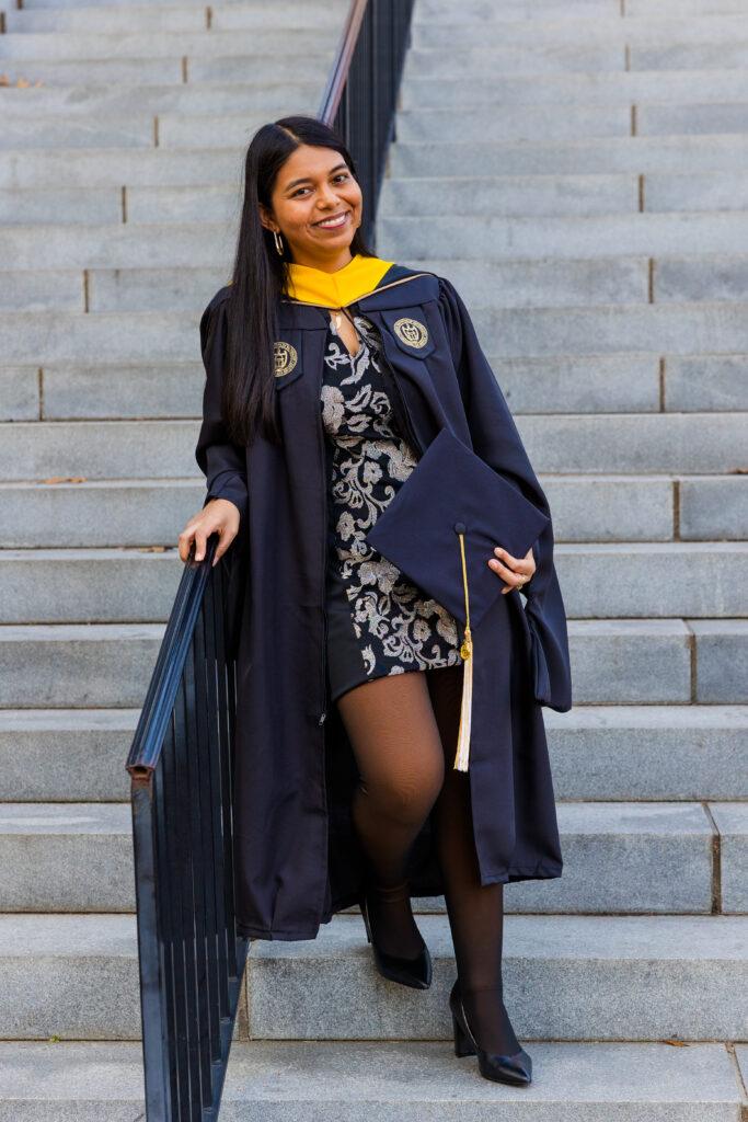 Full body graduation portrait of Pallovi standing on Georgia Tech campus stairs leaning on a railing