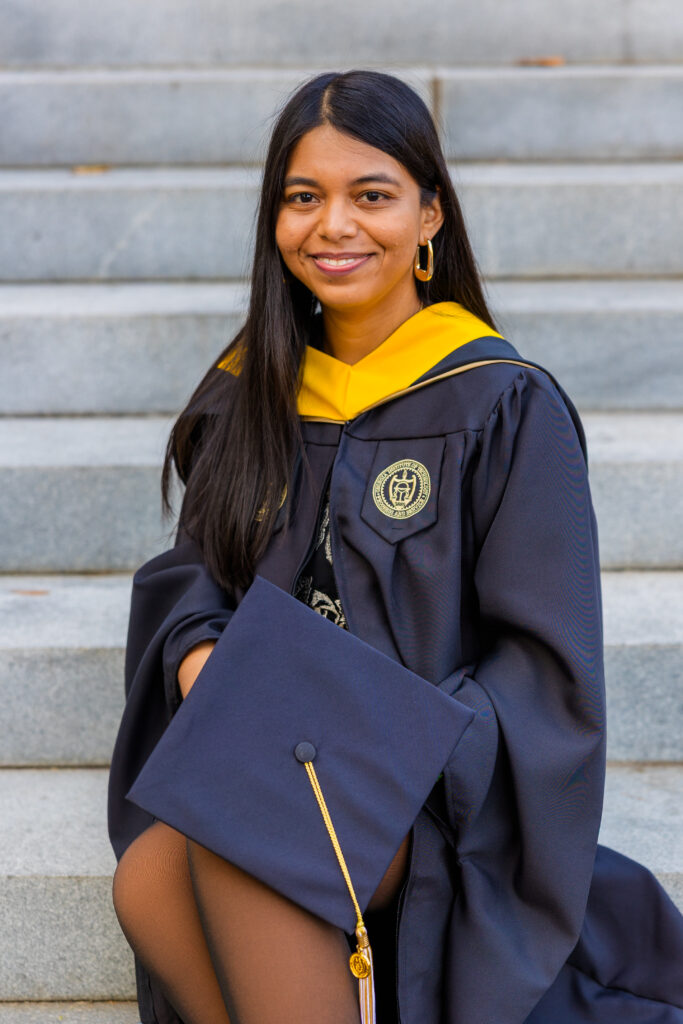 Pallovi sitting on Georgia Tech stairs in her graduation gown holding her cap on her lap