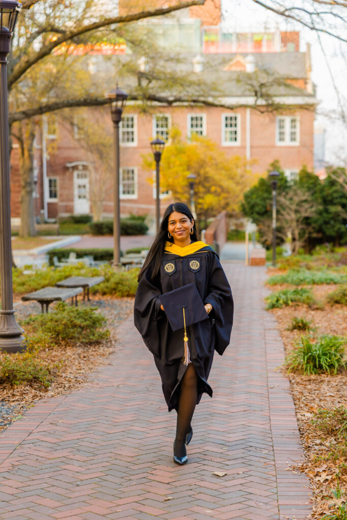 Candid graduation photo of Pallovi walking along a Georgia Tech campus path holding her cap
