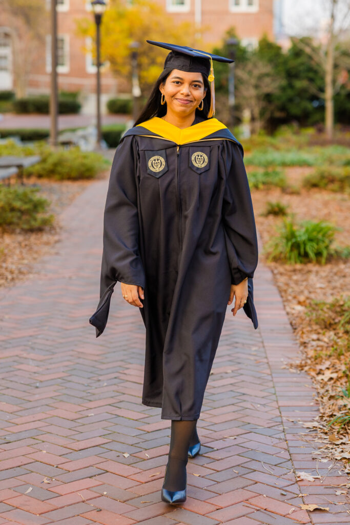 Closer portrait of Pallovi walking on Georgia Tech campus wearing her graduation cap and gown