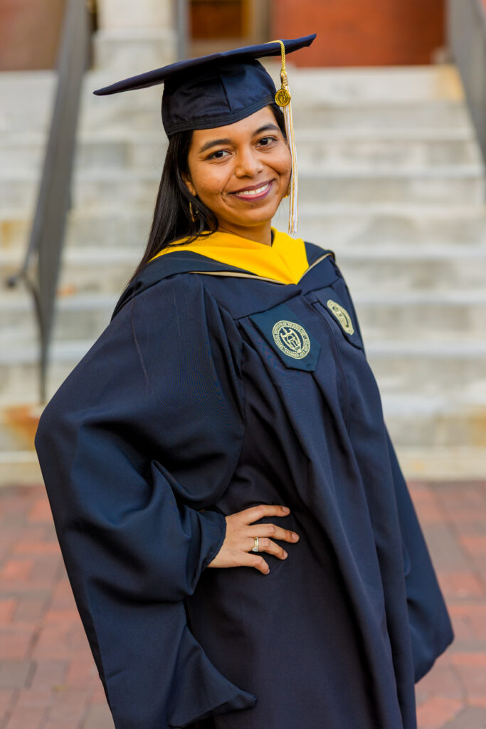 Pallovi smiling in her graduation gown in front of a Georgia Tech campus building