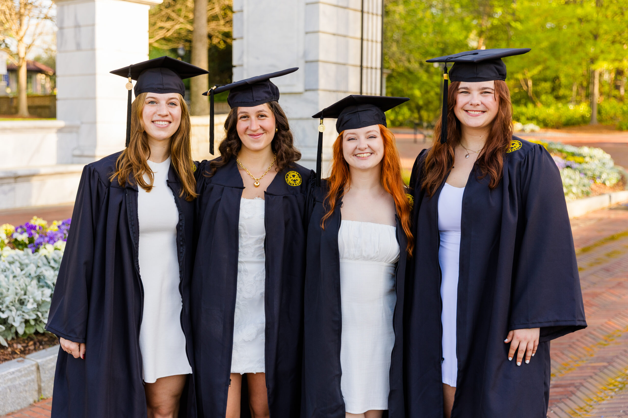 Four college seniors students in cap and gown on Atlanta campus during graduation portraits