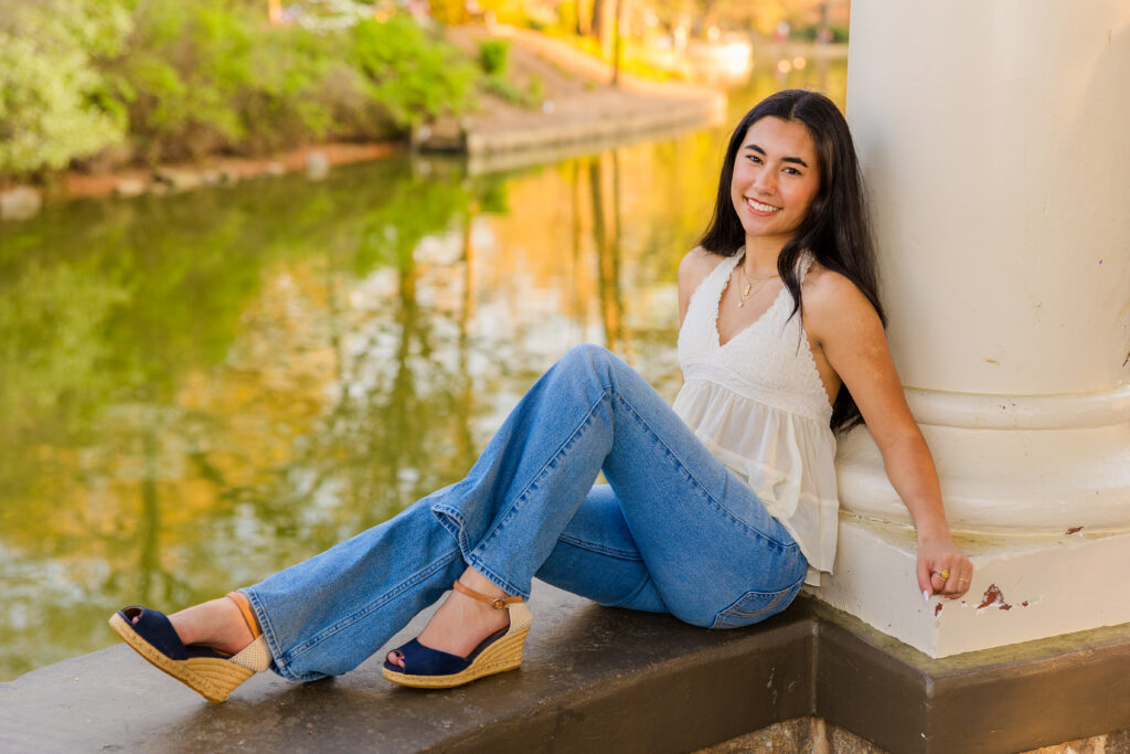Senior sitting in rotunda with pond in background at Piedmont Park Atlanta