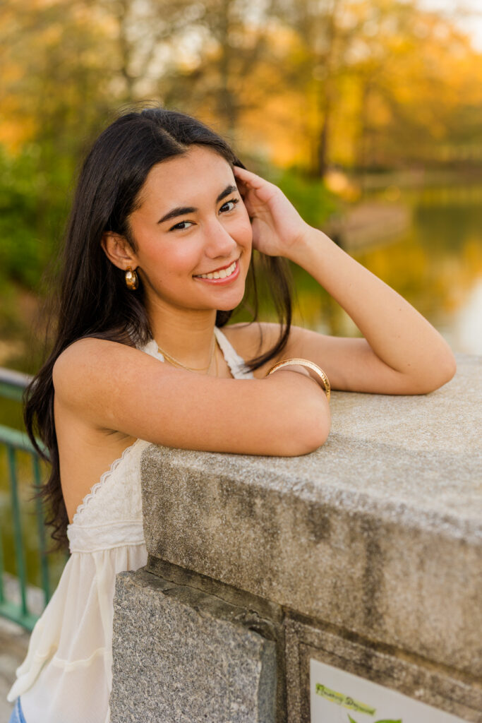 Senior leaning against bridge wall with hand in hair