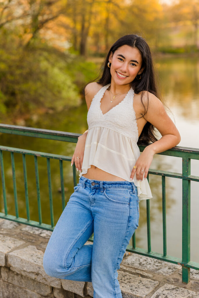 Senior leaning on bridge railing with pond in background