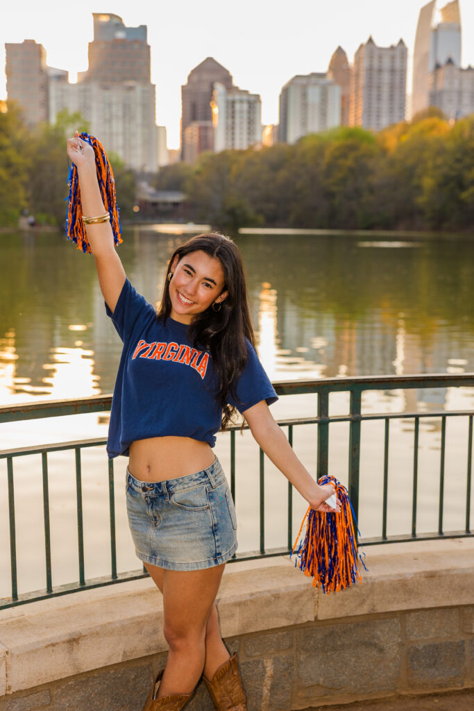 Senior holding pompons in UVA outfit with Atlanta skyline