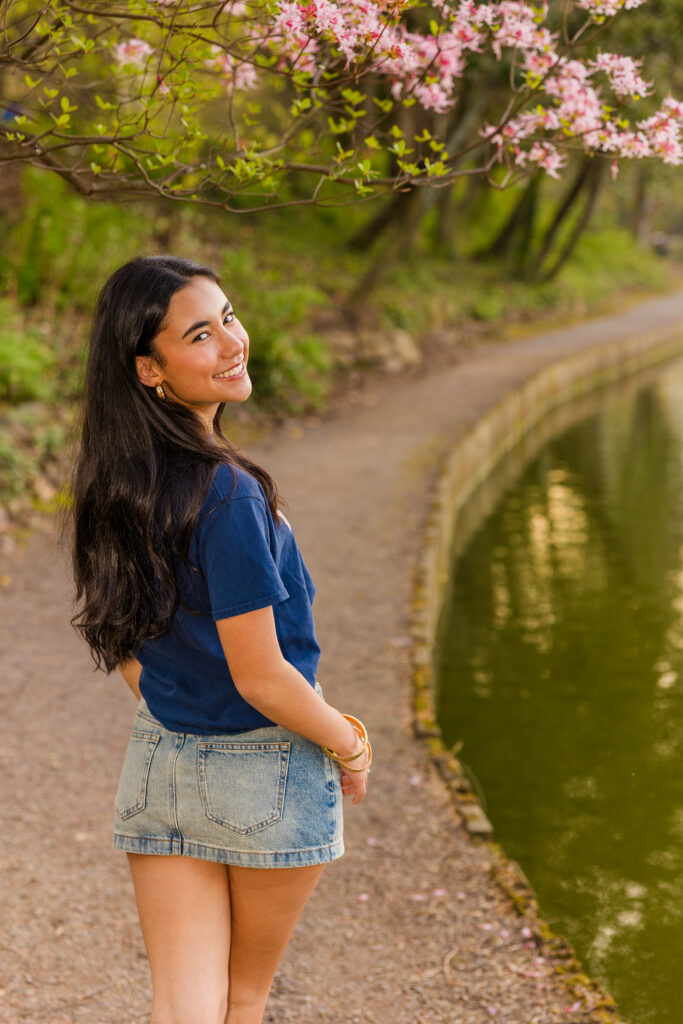 Senior in UVA shirt and denim skirt walking and looking over shoulder