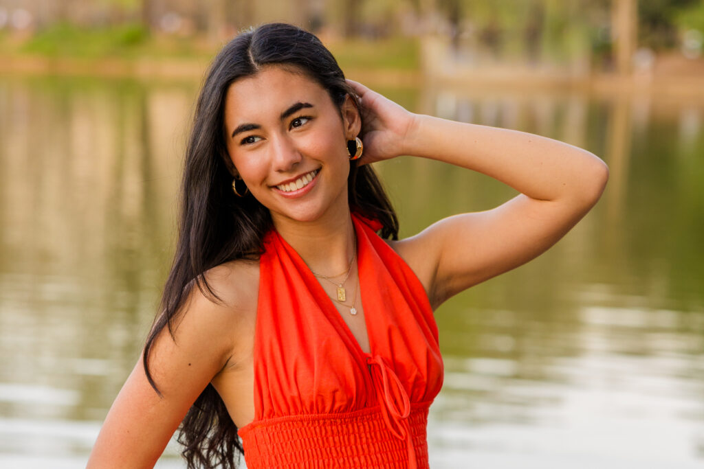 Close-up of senior in orange dress with hand in hair
