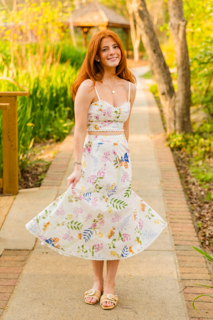 Senior girl spinning on path with greenery during spring session