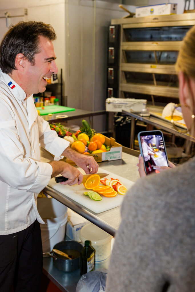 Over-the-shoulder view of daughter filming chef on phone