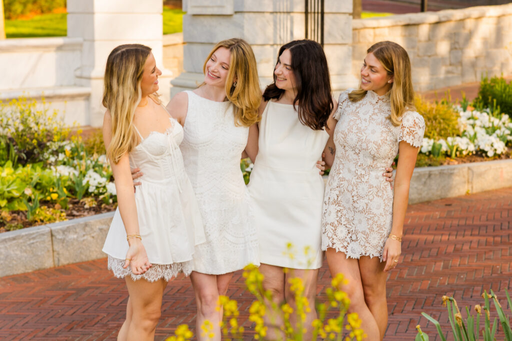 Four girls hugging and looking at each other laughing during Emory graduation photos