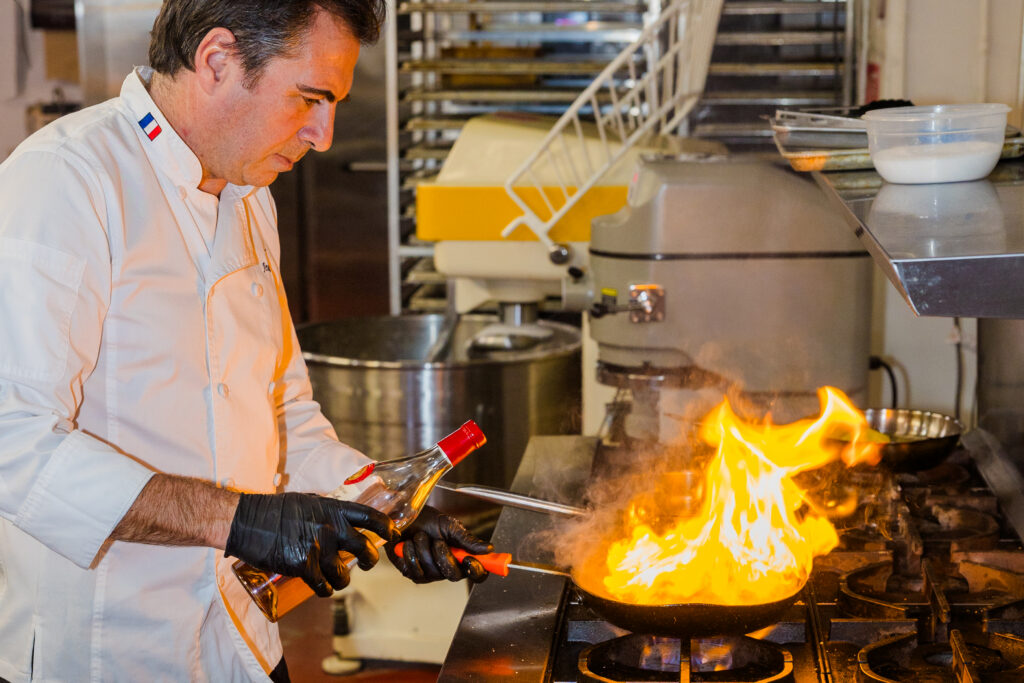 Chef creating flame while cooking with pan and bottle