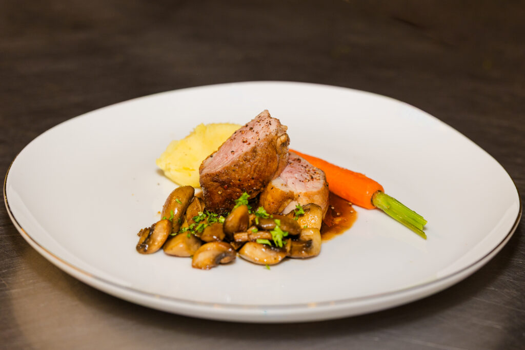 Close-up of plated meat dish with vegetables and mashed potatoes