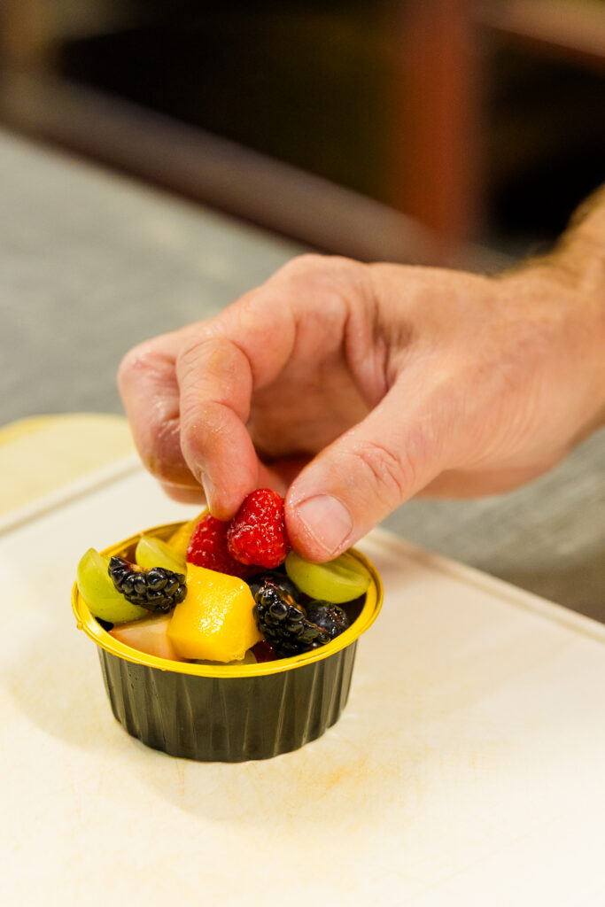 Hand placing final touch on individual salad dish with precision