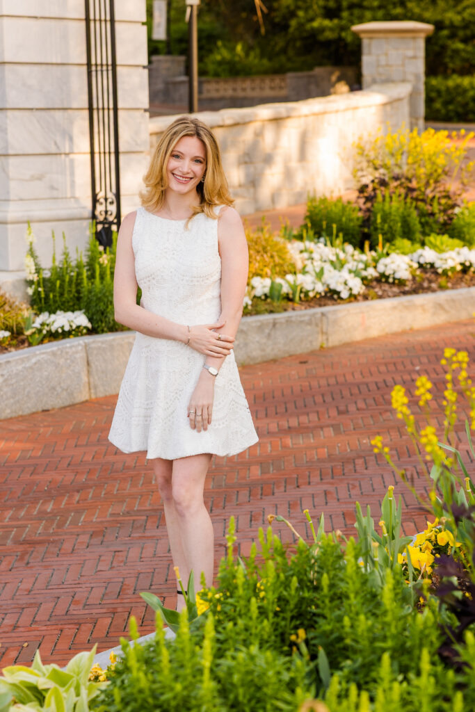 Wide shot of Cate standing on campus path with flowers at Emory graduation session