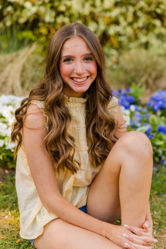 Senior girl smiling in front of flower bed in Piedmont Park Atlanta
