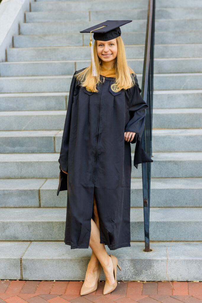 Gabriela leaning against the railing on Georgia Tech stairs in cap and gown