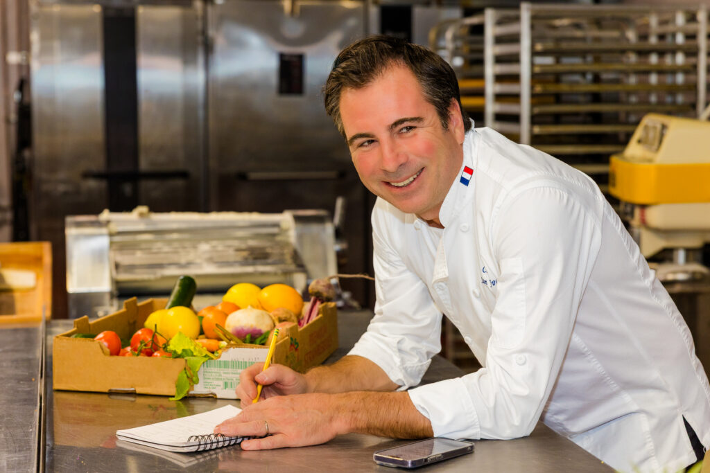 Chef checking order notes on phone and writing in kitchen