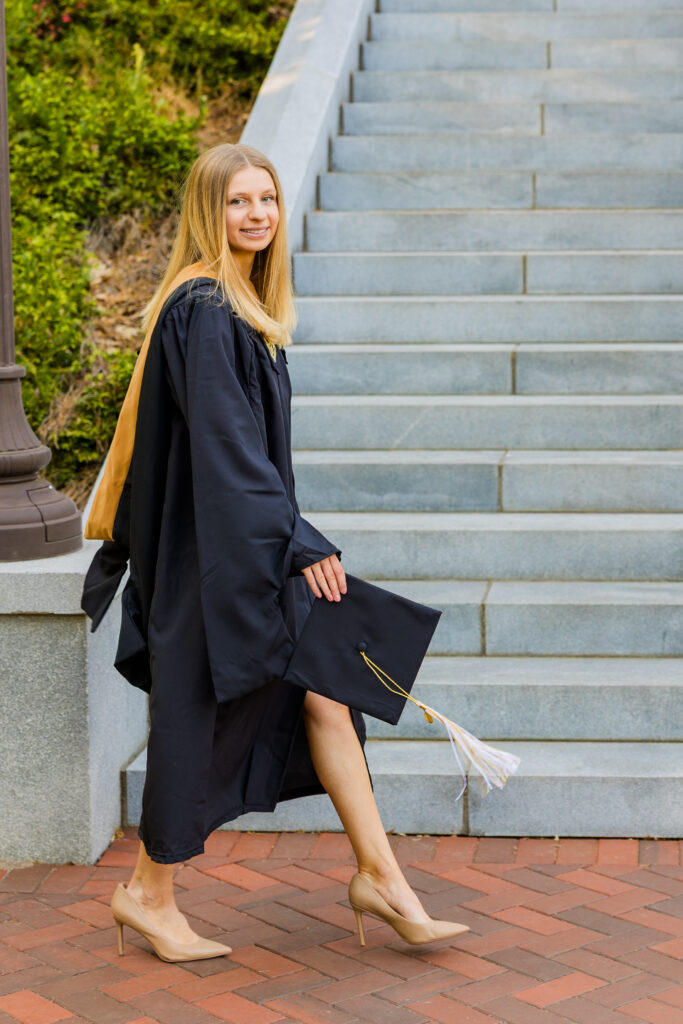 Gabriela walking in front of the Georgia Tech Tower stairs with graduation cap
