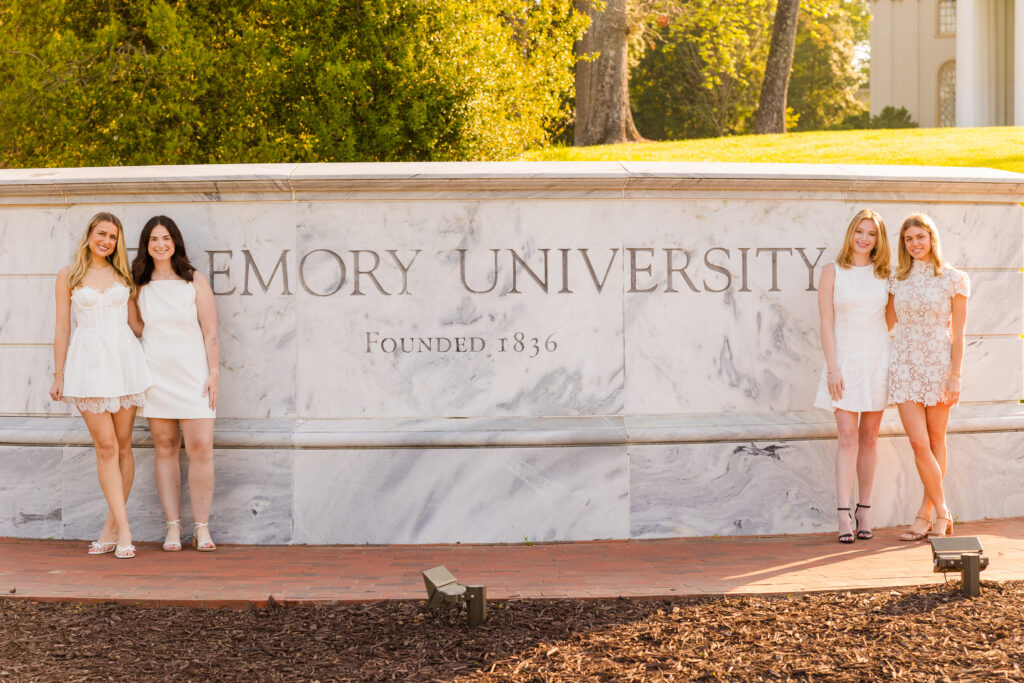 Four girls standing two on each side of Emory wall with sunlight background graduation photos