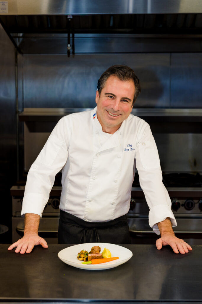 Chef standing behind plated dish smiling at camera