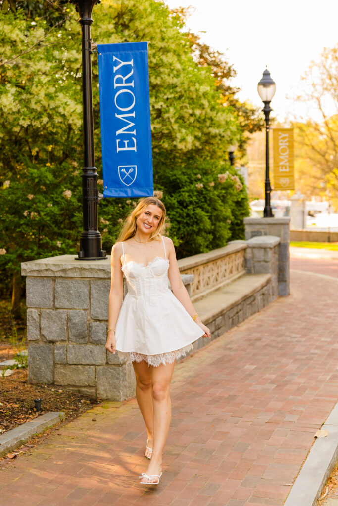 Colbie walking holding her dress with Emory banner in background