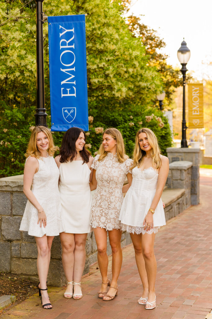 Four girls looking at each other on campus path with Emory banner