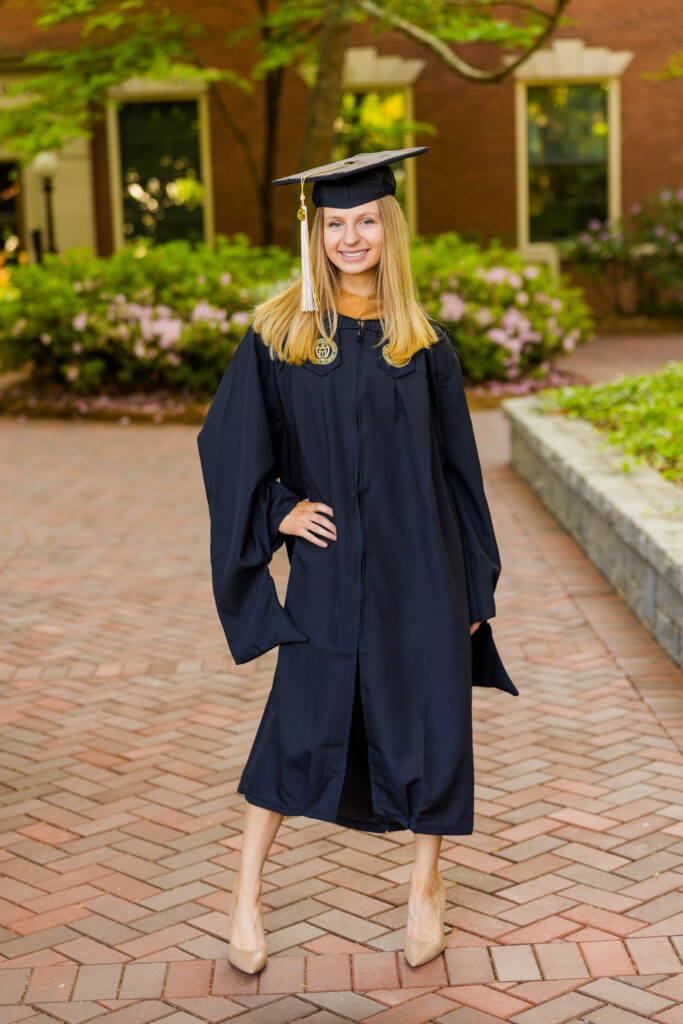 Gabriela posing confidently in cap and gown on Georgia Tech campus