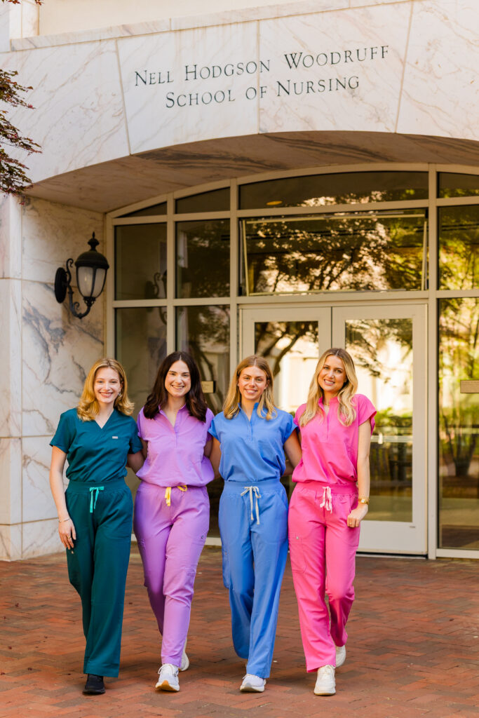 Four girls walking in scrubs in front of Emory nursing building