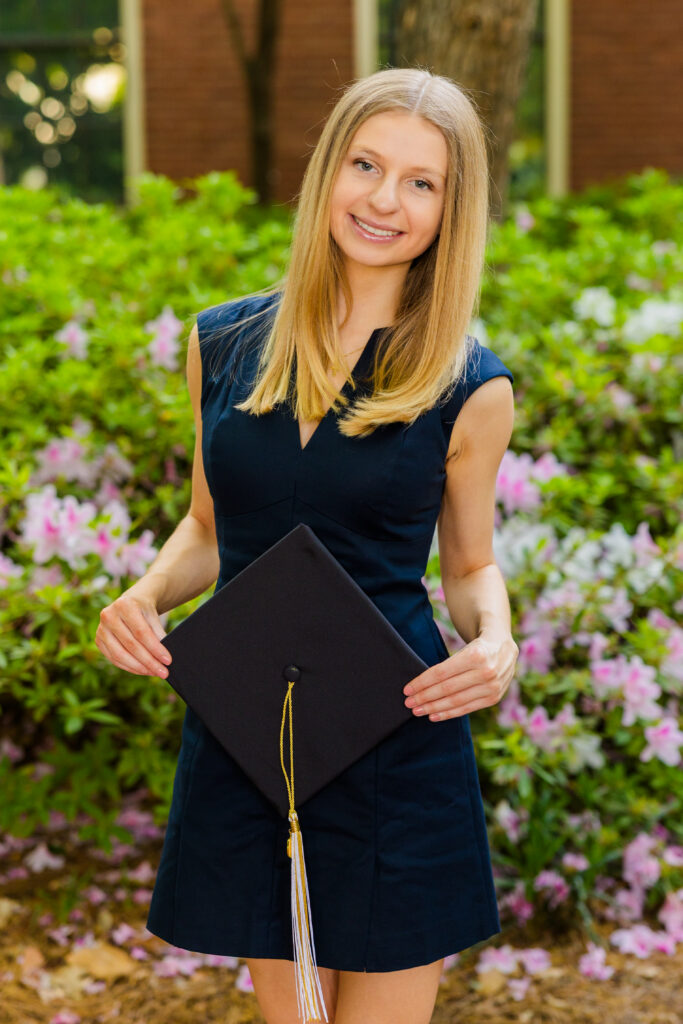 Gabriela standing with flowers in the background during Georgia Tech graduation portraits