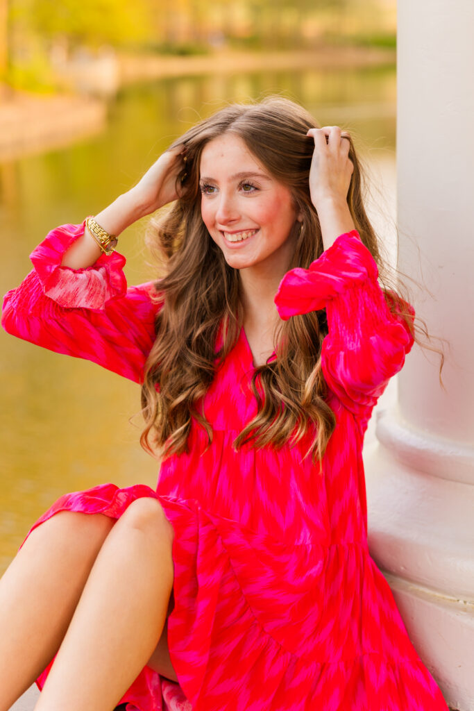 Senior posing by lake with hands in hair