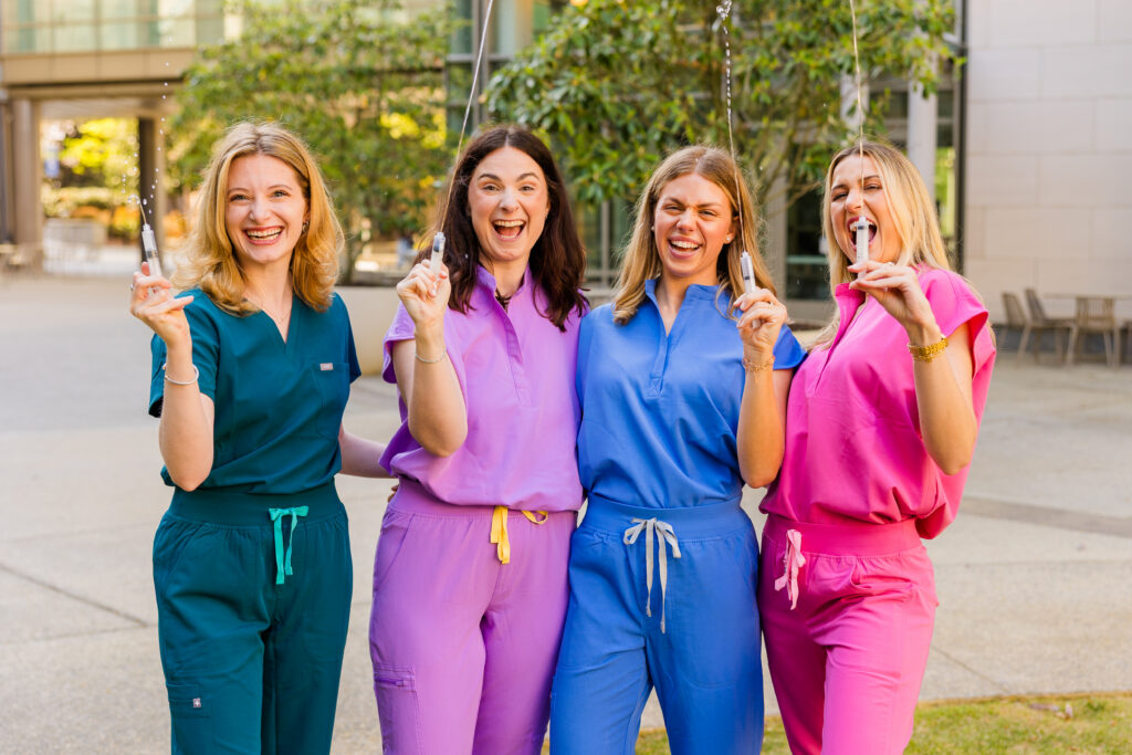 Four girls laughing and spraying flushes during graduation session
