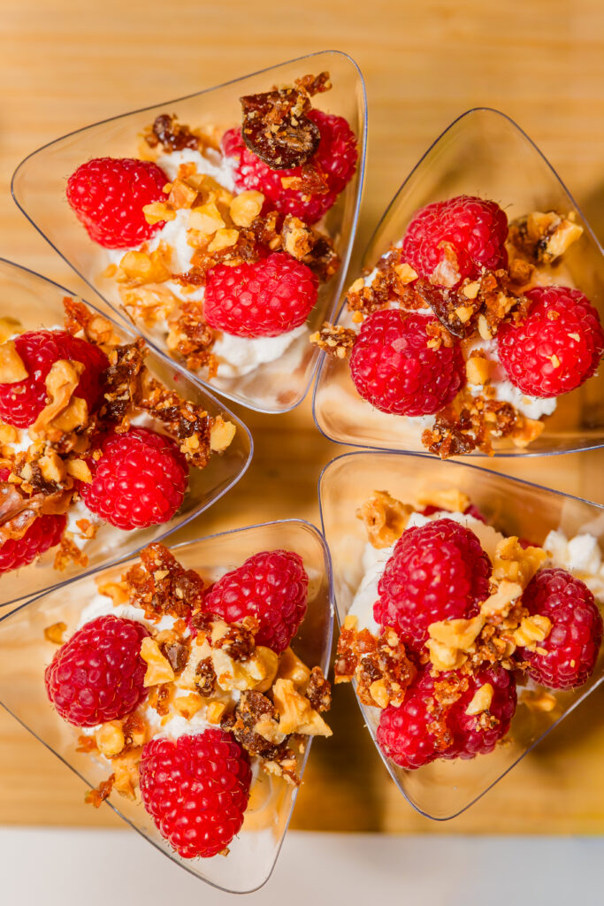 Overhead shot of dessert bites with cream, nuts and raspberries