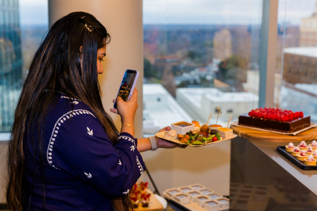Woman taking photo of beautifully plated food at corporate event